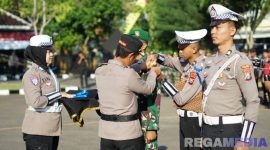 Caption: Kapolres Sampang AKBP Hartono pasang pita kepada personel TNI, saat apel Operasi Patuh Semeru 2025, (sumber foto: Humas Polres Sampang). 