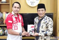 Caption: Kepala Rutan Sampang Kamesworo, memberikan buku karya warga binaan kepada Sekdakab Sampang, Yuliadi Setiyawan, (dok. regamedianews). 
