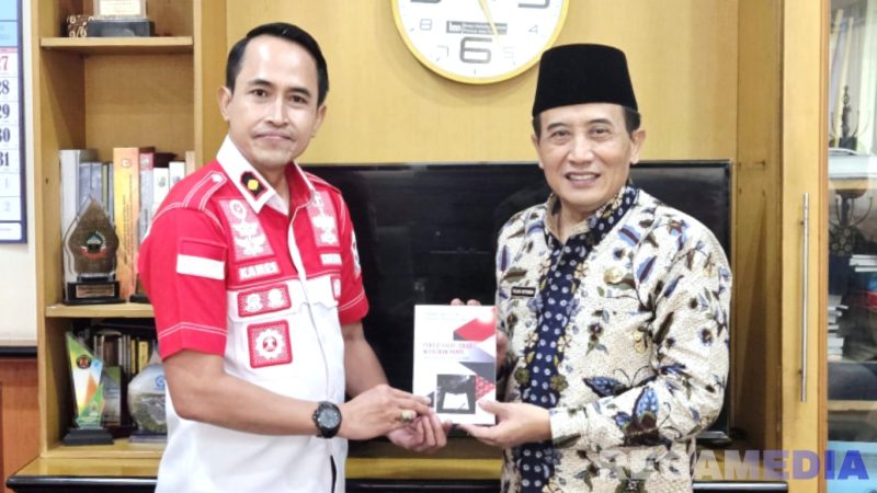 Caption: Kepala Rutan Sampang Kamesworo, memberikan buku karya warga binaan kepada Sekdakab Sampang, Yuliadi Setiyawan, (dok. regamedianews). 