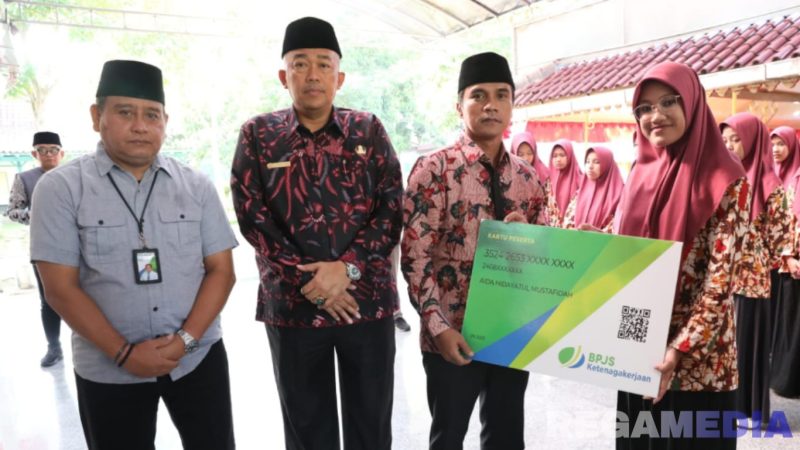 Caption: Bupati Bangkalan Lukman Hakim, menyerahkan secara simbolis kartu peserta BPJS Ketenagakerjaan kepada perwakilan peserta Kafilah MTQ, (foto istimewa). 