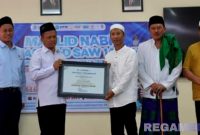 Caption: Rektor UTM, Prof. Dr. Safi’, secara langsung menyerahkan sertifikat akreditasi kepada Ketua Jurusan Manajemen, Fathor AS. 