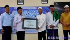 Caption: Rektor UTM, Prof. Dr. Safi’, secara langsung menyerahkan sertifikat akreditasi kepada Ketua Jurusan Manajemen, Fathor AS. 