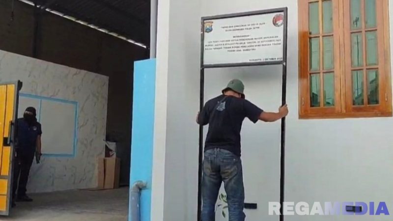 Caption: polisi tak berseragam, pasang plang penyitaan terhadap rumah oknum kades terlibat kasus TPPU dan narkoba, (dok. regamedianews). 