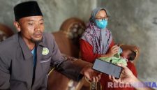 Caption: Rosyid Latif didampingi istri dan bayi yang ditemukan, saat ditemui awak media di rumahnya di Desa Astapah, (dok. regamedianews). 