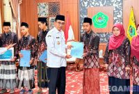 Caption: Bupati Pamekasan KH Kholilurrahman, menyerahkan reward kepada 6 peserta juara MTQ tingkat Provinsi Jawa Timur, (dok. regamedianews). 