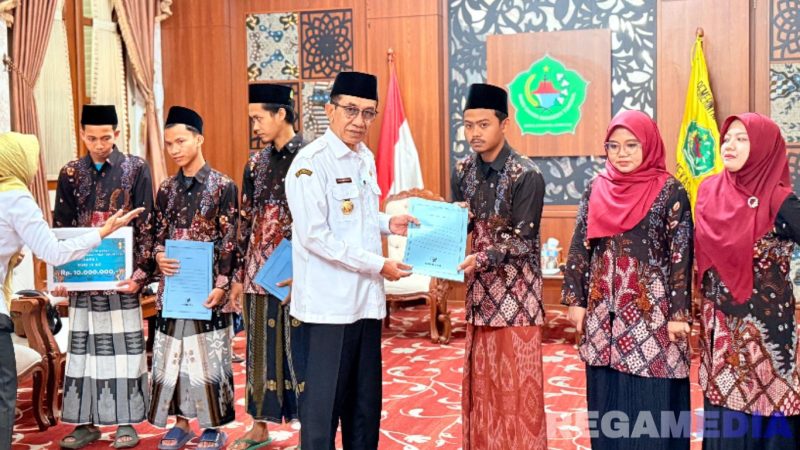 Caption: Bupati Pamekasan KH Kholilurrahman, menyerahkan reward kepada 6 peserta juara MTQ tingkat Provinsi Jawa Timur, (dok. regamedianews). 