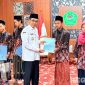 Caption: Bupati Pamekasan KH Kholilurrahman, menyerahkan reward kepada 6 peserta juara MTQ tingkat Provinsi Jawa Timur, (dok. regamedianews). 