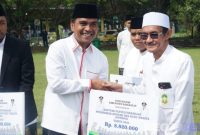Caption: Bupati Bangkalan Lukman Hakim, menyerahkan bantuan dana insentif secara simbolis kepada guru ngaji, (dok. regamedianews). 