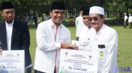 Caption: Bupati Bangkalan Lukman Hakim, menyerahkan bantuan dana insentif secara simbolis kepada guru ngaji, (dok. regamedianews). 