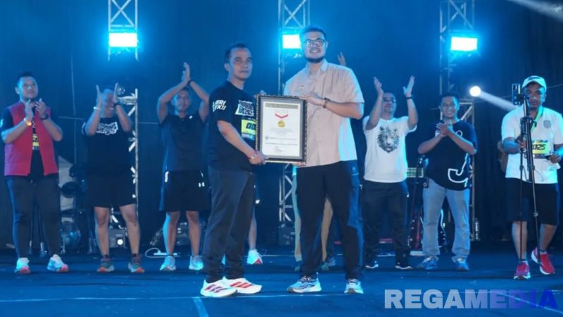 Caption: Bupati Bangkalan Lukman Hakim, menerima reward rekor muri lomba lari dengan penggunaan gelang bercahaya terbanyak, (dok. regamedianews). 