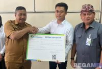 Caption: Kepala BPJS Ketenagakerjaan Cabang Madura, Indriyatno, dampingi Ketua Satgas MBG Bangkalan menyerahkan sertifikat kepesertaan kepada pekerja program MBG, (dok. foto istimewa). 