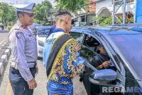 Caption: Polantas gandeng Duta Lantas Polres Sampang, membagikan brosur sosialisasi Operasi Zebra Semeru 2025 kepada pengendara, (sumber foto: Polantas Sampang). 