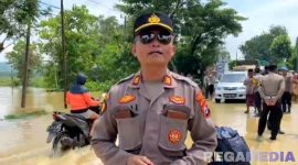 Caption: Plh Kasi Humas Polres Sampang AKP Eko Puji Waluyo, saat melaporkan kondisi banjir dan arus lalulintas di jalan raya Jrengik, (dok. regamedianews). 