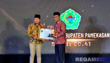 Caption: Bupati Pamekasan KH Kholilurrahman menerima piagam penghargan kabupaten terbaik dalam penerapan keterbukaan informasi publik, (dok. Kursi, Rega Media). 