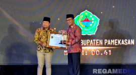 Caption: Bupati Pamekasan KH Kholilurrahman menerima piagam penghargan kabupaten terbaik dalam penerapan keterbukaan informasi publik, (dok. Kursi, Rega Media). 
