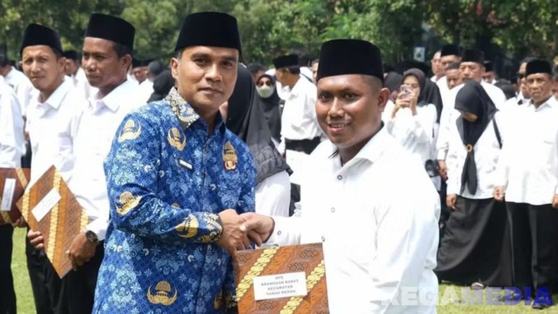 Caption: Bupati Bangkalan Lukman Hakim menyerahkan SK kepada anggota BPD usai pengukuhan, (dok. Syafin, Rega Media). 