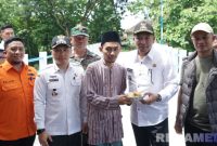 Caption: usai peresmian Jembatan Desa Daleman, Bupati Sampang H Slamet Junaidi memberikan potongan tumpeng kepada salah satu tokoh agama desa setempat, (sumber foto: Diskominfo Sampang).