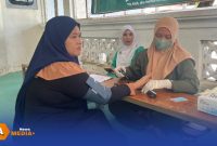 Caption: petugas kesehatan tengah memberikan pelayanan cek kesehatan kepada warga, dalam kegiatan CKG yang digelar PCNU Sampang, (dok. foto istimewa). 