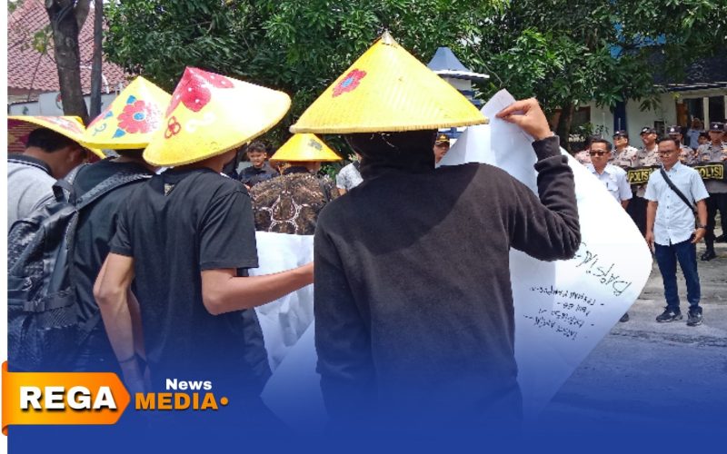 Caption: memakai topi ala petani, sejumlah mahasiswa saat aksi demo di depan Kantor Disperta-KP Sampang, (dok. Harry Rega Media). 